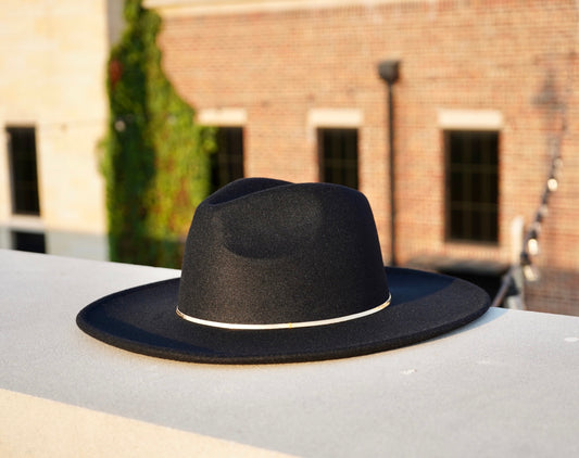 A black wide brim fedora hat with a gold herringbone headband.