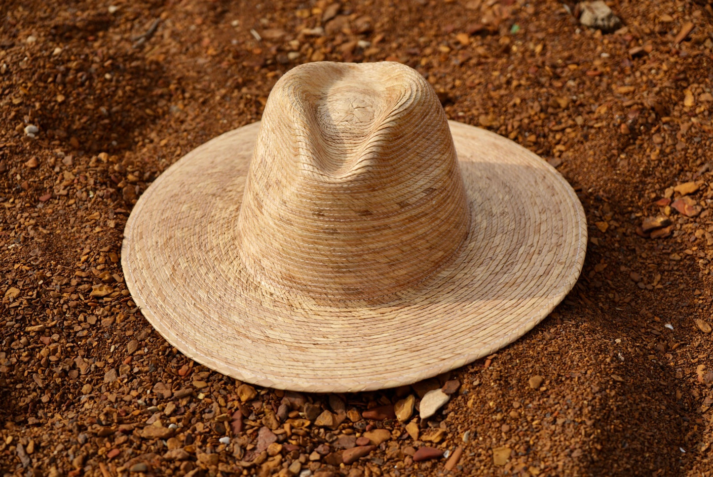 A dark tan color large brim palm sun hat.